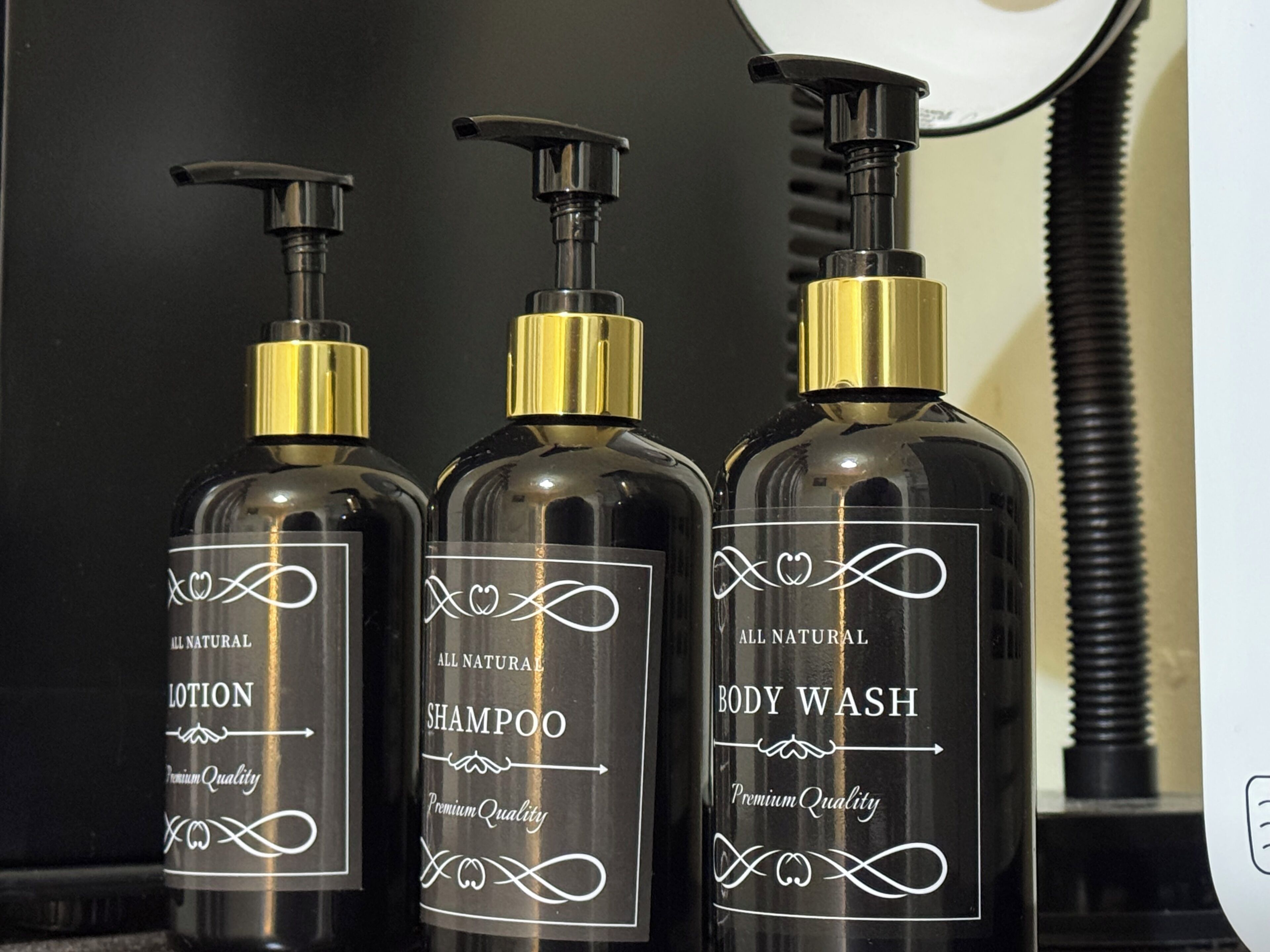 Three bottles of lotion, shampoo, and body wash with pumps and labels indicating premium quality and all natural ingredients.