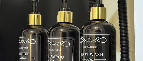 Drei Flaschen Lotion, Shampoo und Duschgel mit Dosierern und Etiketten, die für hochwertige Qualität und natürliche Inhaltsstoffe werben.