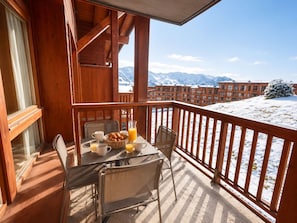 A wooden balcony with a table set for breakfast, overlooking a snowy mountain landscape. - T3 skis aux pieds | Terrasse vue sur les pistes (Bourg-Saint-Maurice)