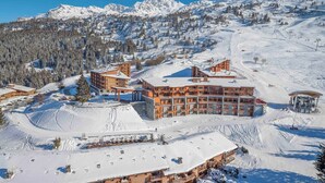 A multi-story hotel with a ski slope in the background.
