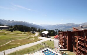A mountain resort with a pool, a building with balconies, and a clear view of the surrounding mountains. - T4 au pied des pistes | Accès piscine | Balcon (Bourg-Saint-Maurice)