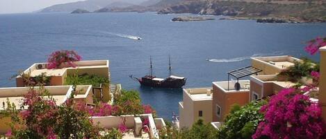 A coastal town with buildings, a boat, and a mountainous backdrop.