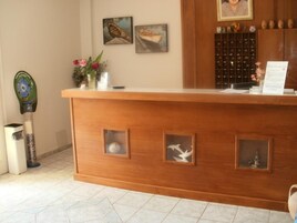 Un mostrador de recepción con detalles de madera, un jarrón con flores y cuadros en la pared.