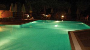A swimming pool with a tiled deck and a few umbrellas. - Ormos Atalia Village (Mylopotamos)