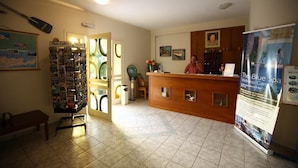 A reception area with a wooden desk, a photo gallery, and a wellness center sign. - Ormos Atalia Village (Mylopotamos)