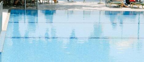 Zona de piscina con sillas de descanso y vista al mar.