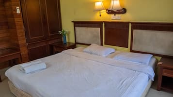A hotel room with a large bed, two bedside tables, a nightstand with a lamp, and a wall-mounted light fixture.