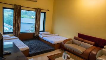 A hotel room with a bed, a sofa, a small table, and a TV.