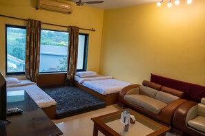 A hotel room with a bed, a sofa, a small table, and a TV.
