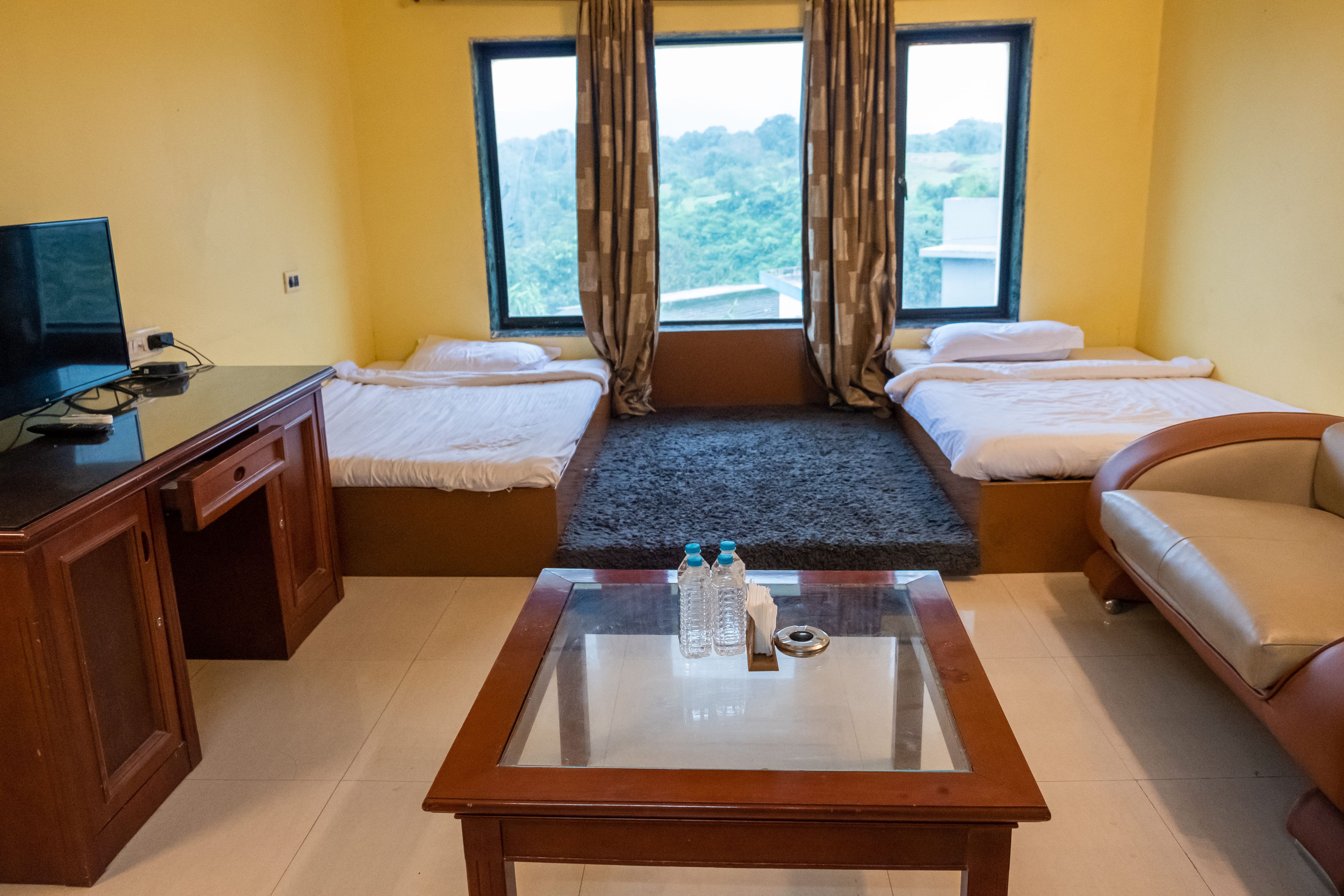 Ein Hotelzimmer mit Bett, Sofa, Fernseher und Couchtisch mit Wasserflaschen.