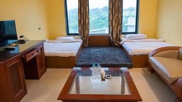 Ein Hotelzimmer mit Bett, Sofa, Fernseher und Couchtisch mit Wasserflaschen.