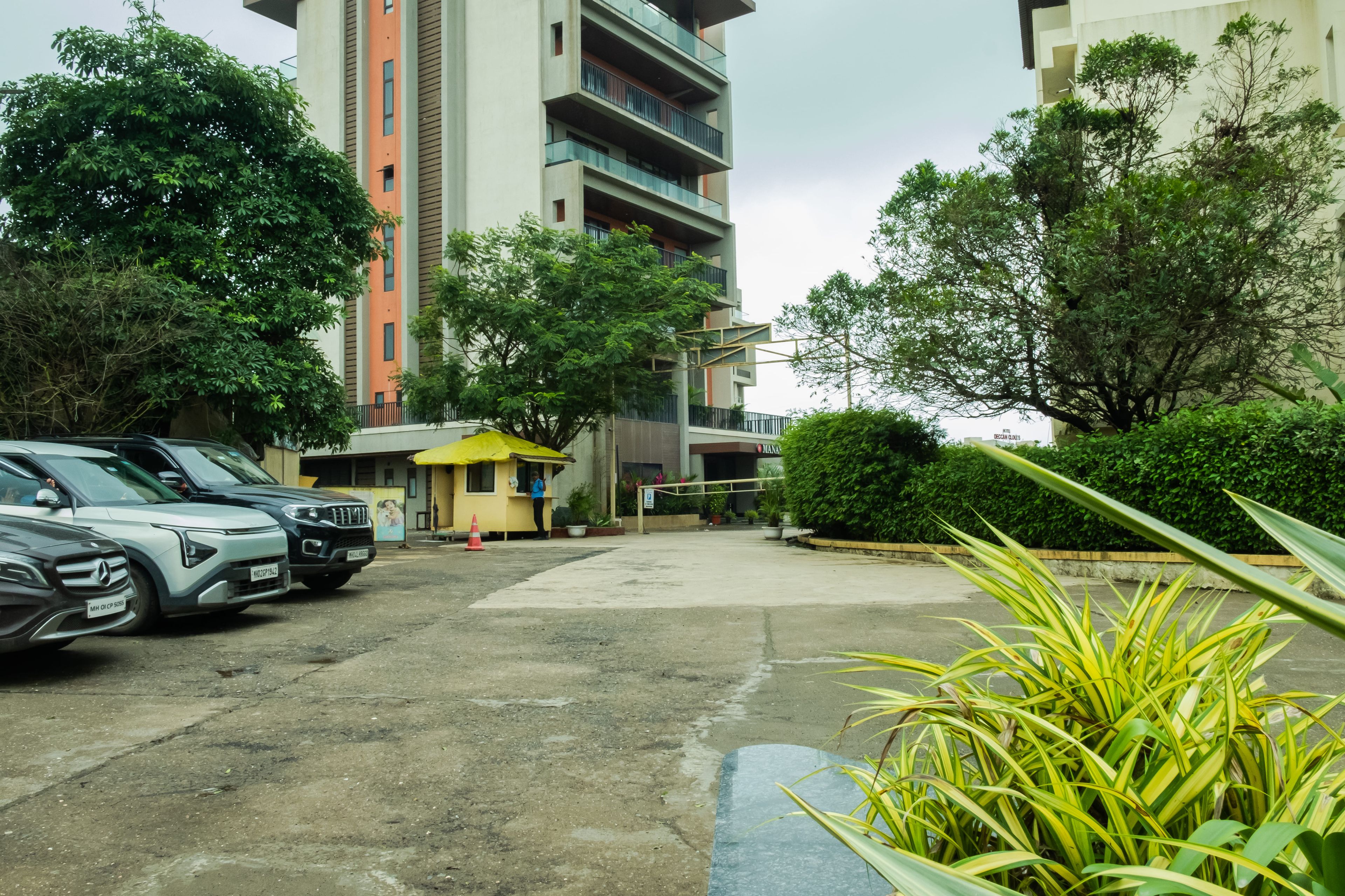 A parking area with multiple cars, a small kiosk, and a building with balconies.