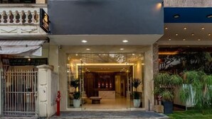 Um hotel chamado 'BLUZEN HOTEL' com fachada moderna, janelas amplas e entrada bem iluminada.