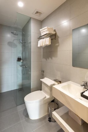 Un baño moderno con cabina de ducha de vidrio, inodoro blanco y tocador con espejo.
