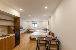 A compact hotel room with a kitchenette, a dining area, and two single beds. - Bluzen Hotel (Da Nang)