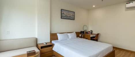 A bedroom with a bed, bedside table, nightstand, and a small desk with a chair.