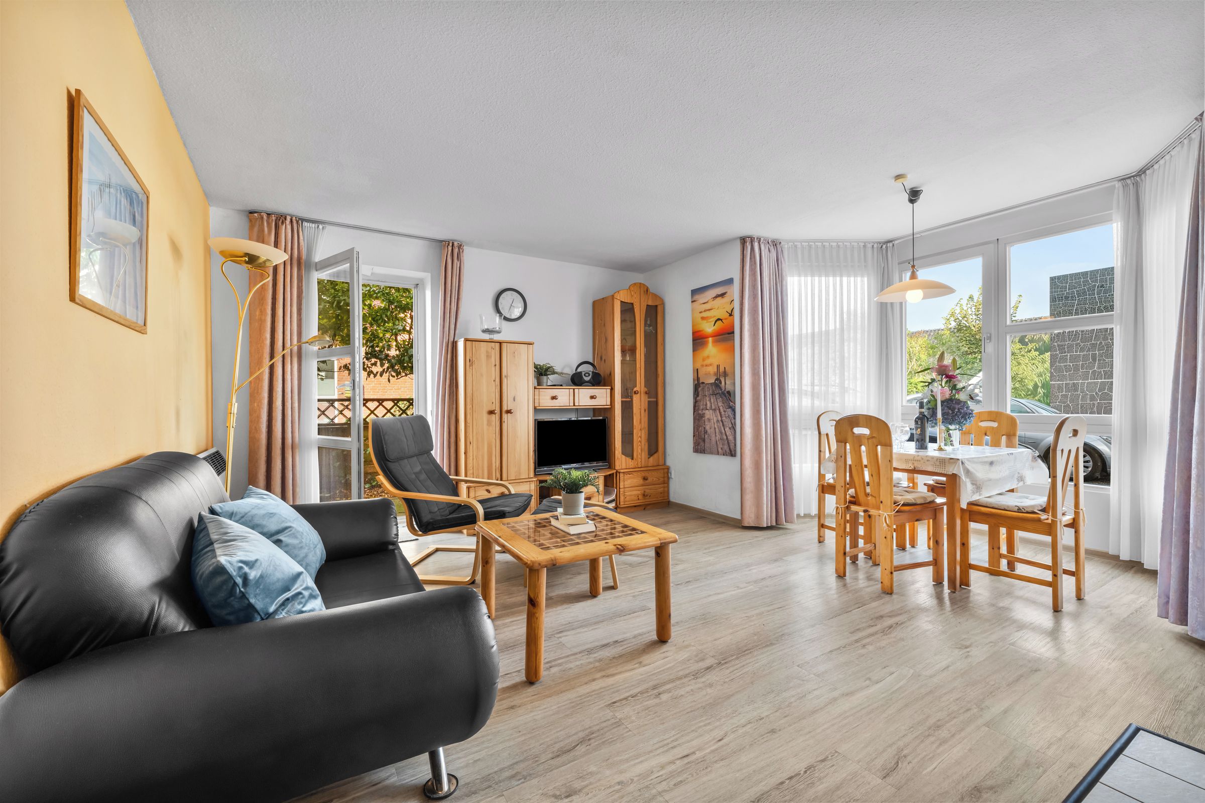 A living room with a sofa, chairs, a coffee table, a TV, and a dining area with a table and chairs.