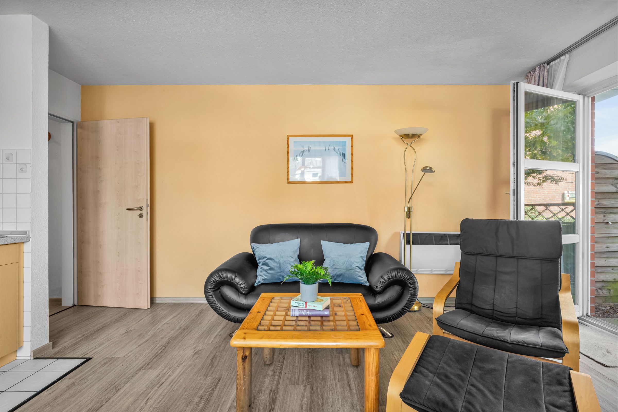 Ein Wohnzimmer mit einem schwarzen Ledersofa, einem Holztisch und einem schwarzen Sessel.