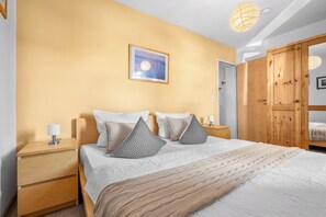Una habitación de hotel con cama, mesitas de noche, armario y un cuadro en la pared.