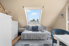 A bedroom with a bed, a dresser, a chair, and a window with a view of trees. - Küstenperle – Your Cozy Holiday Home for a Relaxing Getaway (Schönberg (Holstein))