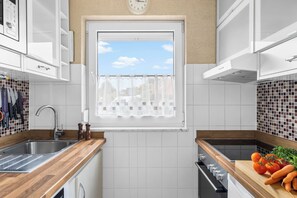 A modern kitchen with white cabinetry, a window with a view, a stainless steel sink, and a wooden countertop. - Küstenperle – Your Cozy Holiday Home for a Relaxing Getaway (Schönberg (Holstein))