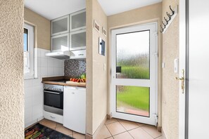 A compact kitchen with a built-in oven, a microwave, and a sink. - Küstenperle – Your Cozy Holiday Home for a Relaxing Getaway (Schönberg (Holstein))