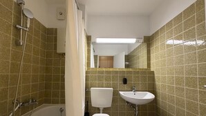A bathroom with a bathtub, toilet, and sink, all with modern fixtures. - Romantic lakeside cabin with a balcony and indoor communal pool in Uhldingen-Mühlhof (Uhldingen-Mühlhofen)