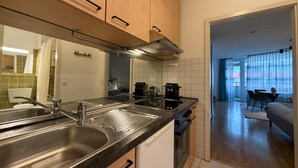 A modern kitchen with stainless steel appliances, a built-in oven, and a dining area with a table and chairs. - Romantic lakeside cabin with a balcony and indoor communal pool in Uhldingen-Mühlhof (Uhldingen-Mühlhofen)