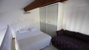 Ein Schlafzimmer mit einem Bett, einem Schlafsofa, einem Kleiderschrank und einer Decke mit Holzbalken.
