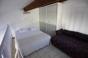 Ein Schlafzimmer mit einem Bett, einem Schlafsofa, einem Kleiderschrank und einer Decke mit Holzbalken.