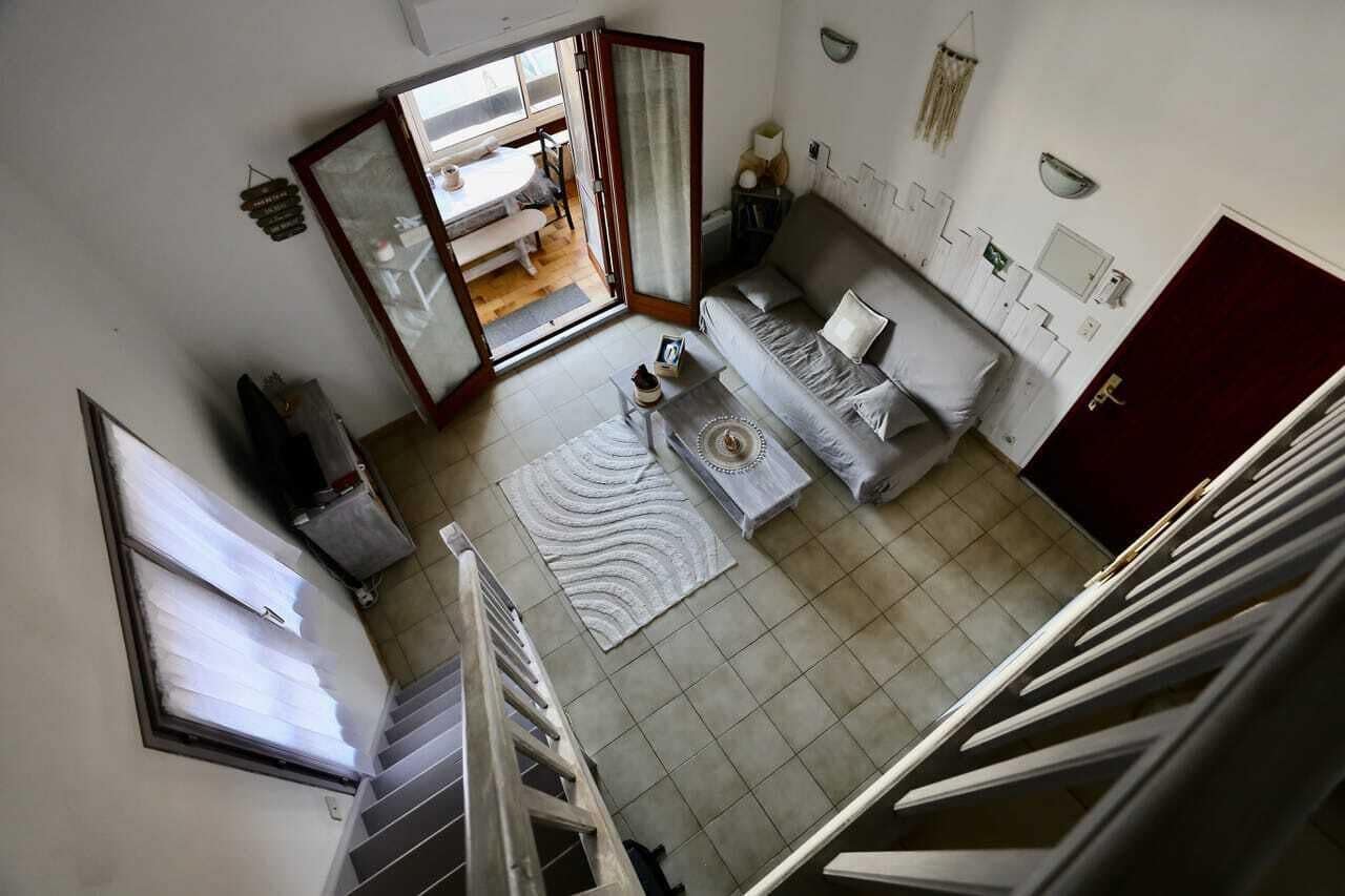 Une pièce comprenant un canapé, une table à manger, un coin cuisine et un escalier.