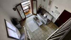 Ein Zimmer mit einer Couch, einem Esstisch, einer Küchenzeile und einer Treppe.