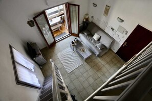 Ein Zimmer mit einer Couch, einem Esstisch, einer Küchenzeile und einer Treppe.