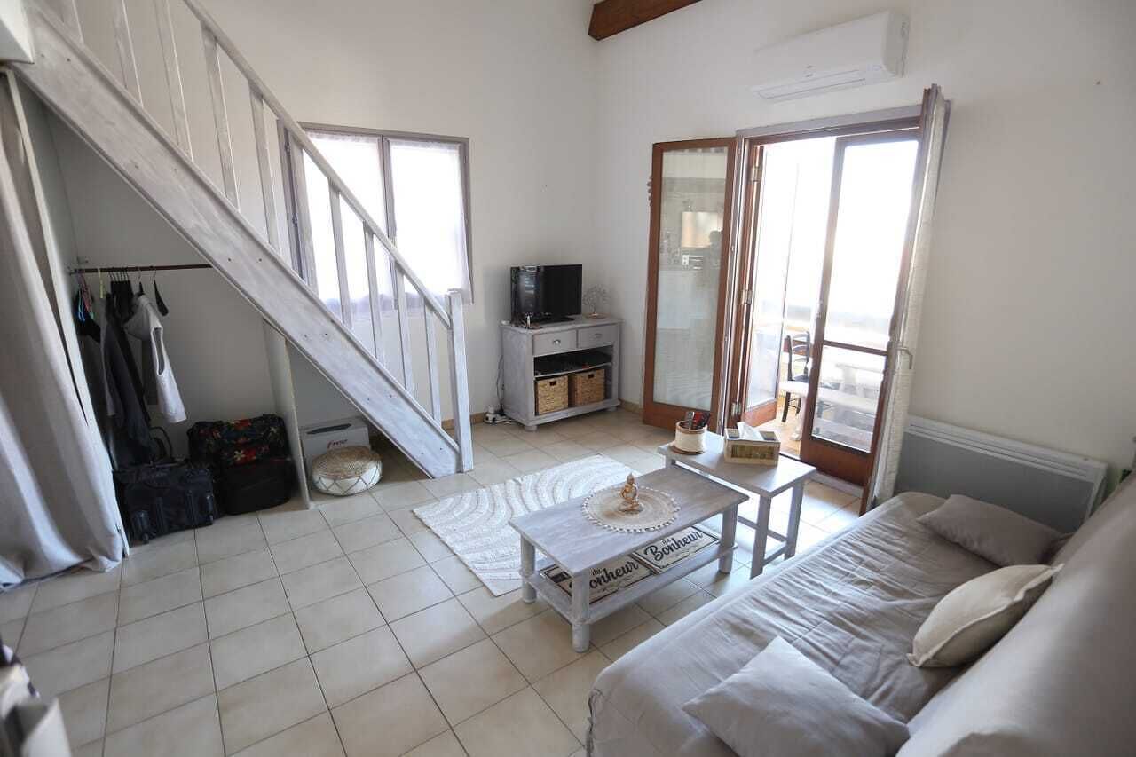 A room with a staircase, a bed, a television, and a window.