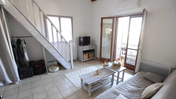 Ein Zimmer mit Treppe, einem Bett, einem Fernseher und einem Fenster.