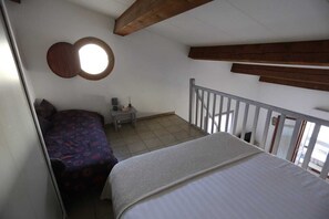 Une chambre à coucher avec un lit, une table de chevet, une lampe et une fenêtre.