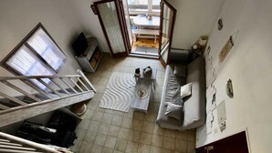 Ein Zimmer mit Treppe, einer Couch, einem Couchtisch und Blick durch eine offene Tür.