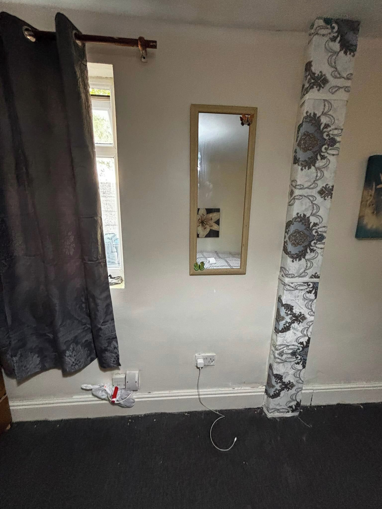 Ein Badezimmer mit Duschvorhang, Spiegel und einer Steckdose an der Wand.
