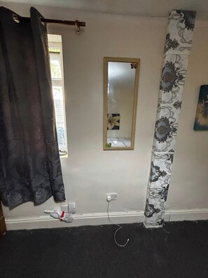 A bathroom with a shower curtain, a mirror, and a power outlet on the wall.