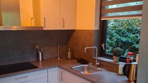 Una cucina moderna con mobili bianchi, lavello in acciaio inossidabile e una finestra con vista sul verde.