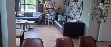Una sala moderna con una mesa de comedor de madera, sillas de cuero y un sofá.