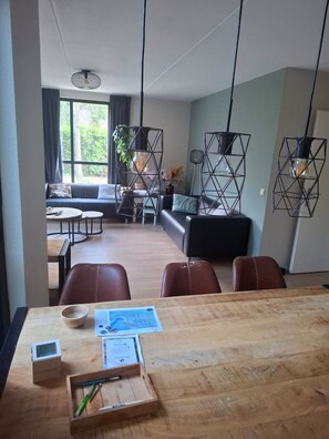 Una sala moderna con una mesa de comedor de madera, sillas de cuero y un sofá.