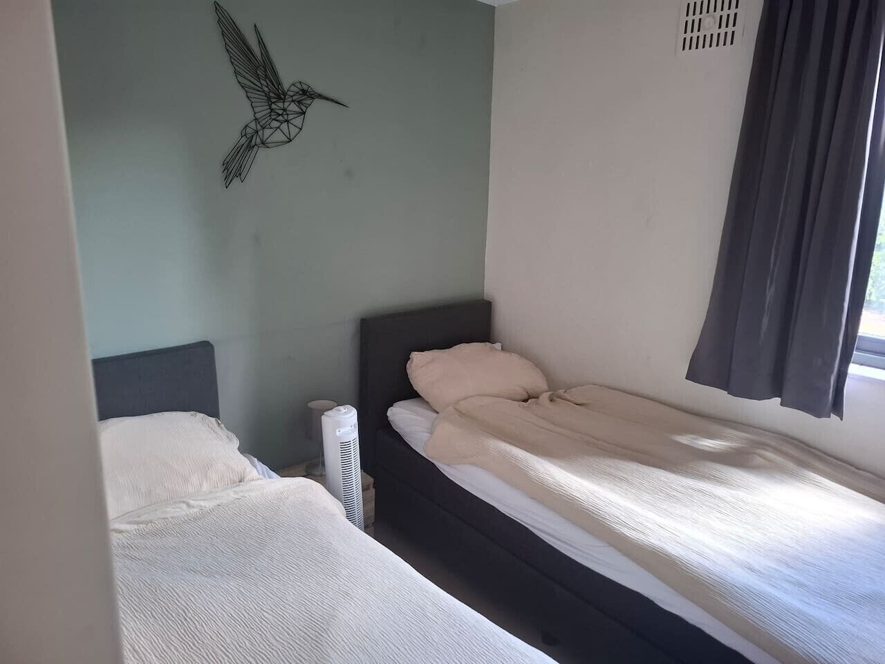 Un dormitorio con dos camas, un calentador y una decoración en la pared.