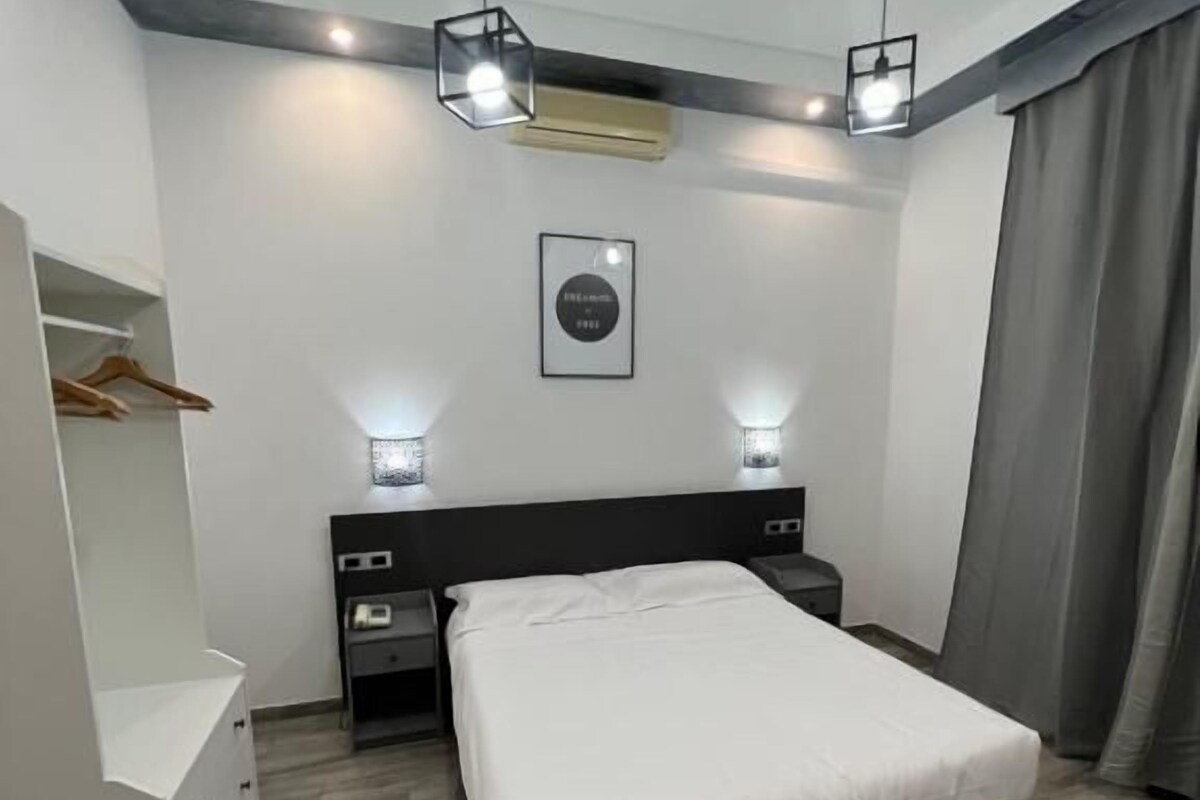 Een moderne slaapkamer met een bed, nachtkastjes, een kledingkast en hanglampen.