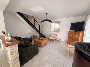 Ein Wohnzimmer mit einer Couch, einem Couchtisch und einem Fernseher auf einem Holzschrank.