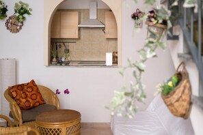 A modern interior with a kitchen visible through an archway, wicker furniture, and decorative plants. - Sanità inside By Dimorra  (Naples)