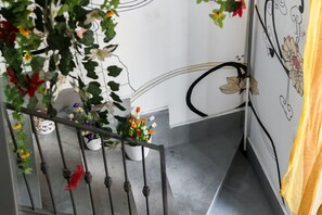 A staircase with a railing, potted plants, and a wall with floral designs. - Sanità inside By Dimorra  (Naples)