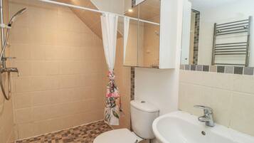 A bathroom with a shower, toilet, sink, and a mirror.