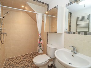 A bathroom with a shower, toilet, sink, and a mirror. - Frome Gazey Barn (Dorchester)