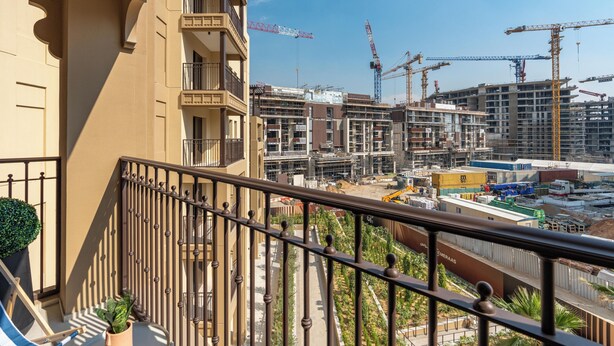 A balcony with a view of a construction site and surrounding buildings. - bnbme - Al Jazi - 2BR (Dubai)